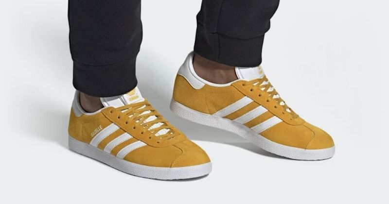 Person wearing yellow and white adidas Gazelle on a white background